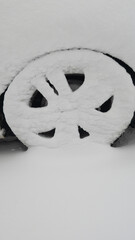 Snow-Covered Wheel Resting in Quiet Winter Scene with Frost on Rim