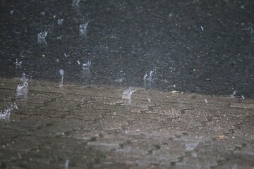 heavy rain falls on the street and splashes in the puddles
