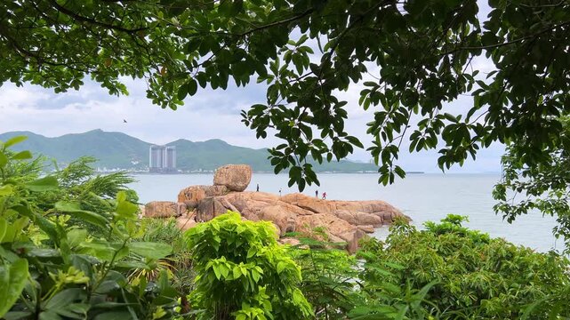 Cape Hon Chong, a garden of stones, at sunset in Nha Trang, the sun's rays turn the rocks and the sea into golden and crimson tones. Mountains, sky, and skyscrapers in the background. 4К