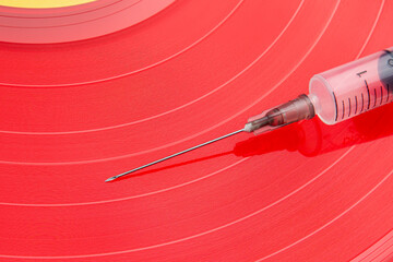Medical Syringe Resting On A Bright Red Vinyl Record Surface