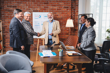 Senior Indian Asian executives applauding and shaking hands after successful business presentation