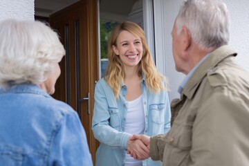 Obraz premium Cheerful Young Caregiver Shaking Hands with a Senior Man at the Door