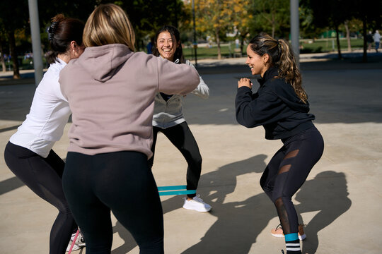 Women exercising outdoors doing squats with resistance bands - Powered by Adobe