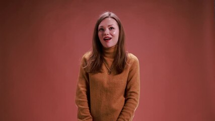 Woman nodding politely while listening and reacting on brown background. Concept of attentive communication, professional interaction visuals, human response for marketing and digital content.