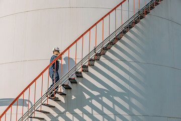 Top view male worker climbs up the ladder inspection stainless tank work at height © chitsanupong