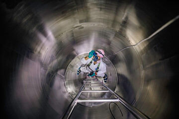 Top view male climbs up the stairs into the tank stainless chemical area confined