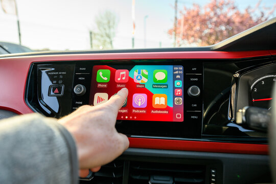 Hand using Apple CarPlay touchscreen inside modern car