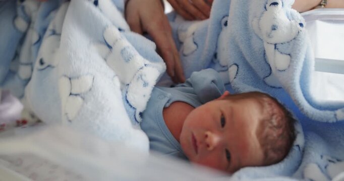 Infant rests soundly swaddled in soft blue blanket with teddy bear pattern, evoking tenderness and new beginnings