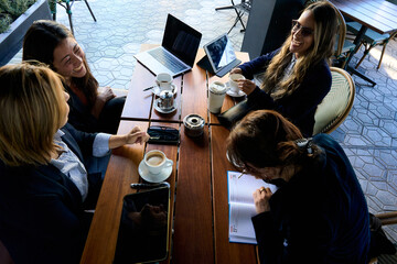 Women business team laughing during outdoor cafe meeting