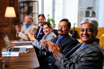 Senior Indian executives applauding successful business presentation in modern corporate office