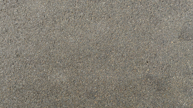 Aerial close-up shot of a uniform, grainy grey surface. Ideal for texture, pattern and background of paved road. Closeup of asphalt and street.