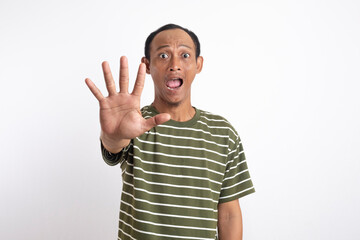 Naklejka premium An Asian wearing a green shirt with white stripes holds up his hand with his palm facing forward, signaling to stop, with a surprised and alert expression. 