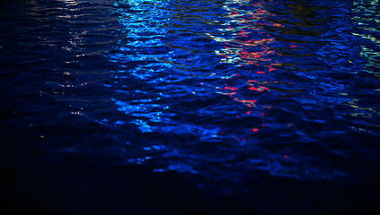 Abstract blue and red light reflections shimmering on dark water surface at night