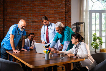 Senior Indian doctors and surgeons analyzing patient data on laptop to plan treatment