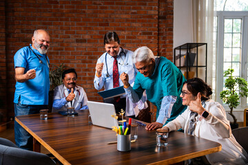 Indian senior doctors clapping after successful medical case discussion on laptop