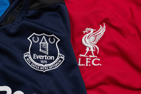 Close-up of Everton and Liverpool football club crests on jerseys, symbolizing the Merseyside derby rivalry.