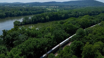 Train traveling beside peaceful river through green countryside in Maryland by the Potomac river at Point of Rocks, MD
