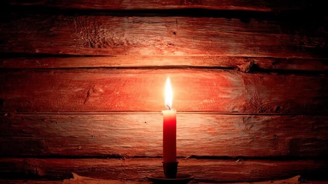 Lit candle against dark wooden background with warm lighting