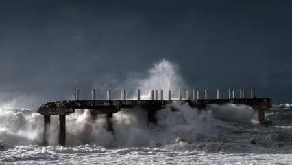  large waves crashing against a damaged pier