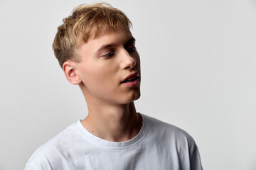 Young man in a white tshirt, studio lighting, side profile with a relaxed expression against a neutral backdrop, minimal setup for fashion or lifestyle use, clean composition, contemporary style