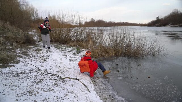 Child slips while exploring icy riverbank.