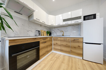 Kuchnia w apartamencie w jasnych kolorach , biel, brązowe fronty szafek, stolik śniadaniowy