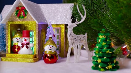 A Christmas house with snowmen on the porch and a snowman with a reindeer nearby