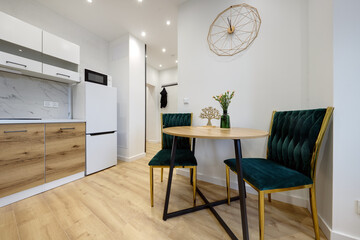 Kuchnia w apartamencie w jasnych kolorach , biel, brązowe fronty szafek, stolik śniadaniowy