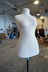 White fabric female dress form or mannequin torso with an adjustable metal stand