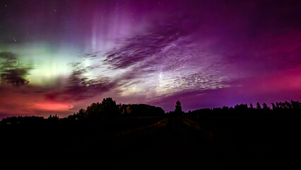 Northern lights dancing over country road in north of Sweden
