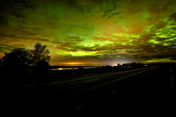 Northern lights dancing over country road in north of Sweden