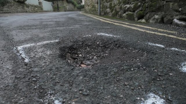 4K: Pothole on road or Street in need of repair. Damaged Tarmac with pot hole. Stock Video Clip Footage
