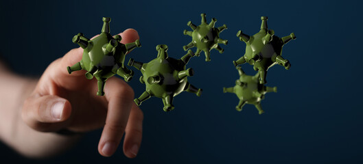 Conceptual image of green virus models held near a human hand. Illustrating concept of pandemics, disease spre