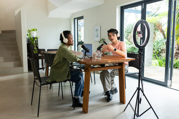 Diverse creators using microphones and headphones near ring light recording podcast in home studio