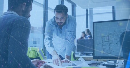 Pointing Middle Eastern man in light shirt leaning over desk in open office, studying blueprints © vectorfusionart