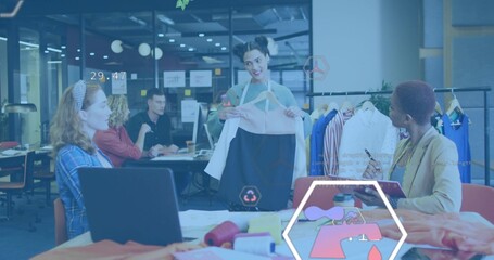 Presenting designer holding dress on hanger in modern studio, wearing apron strap with swatches