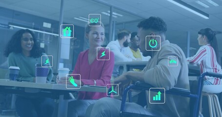 Talking team around table at office breakout, holding cups, with wheelchair and energy icons