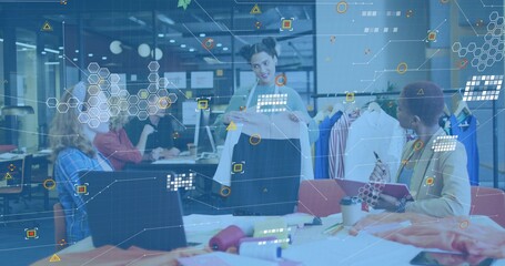 Holding standing woman in light top presenting white blouse in design studio, with fabric swatches