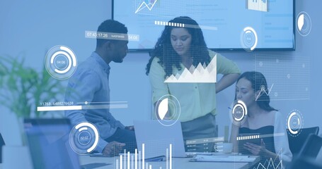 Analyzing team of three in business attire reviewing charts on monitor and laptop in meeting room