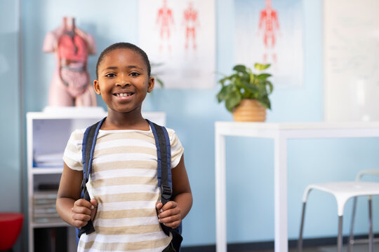 African American youth female standing in clinic holding backpack straps with torso model visible