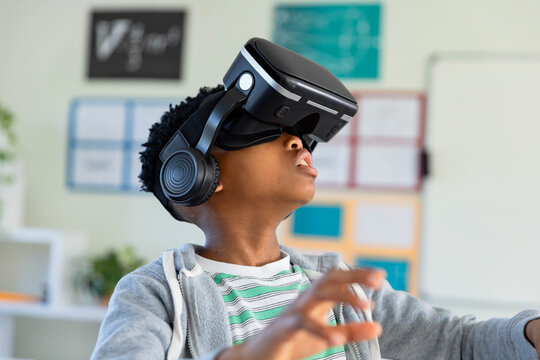 VR headset and headphones are creating immersive classroom scene with hand reaching forward