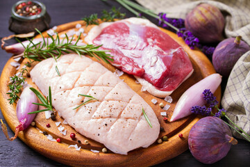 Duck fillets with herbs, shallots and figs on round wooden board prepared for cooking. Raw poultry