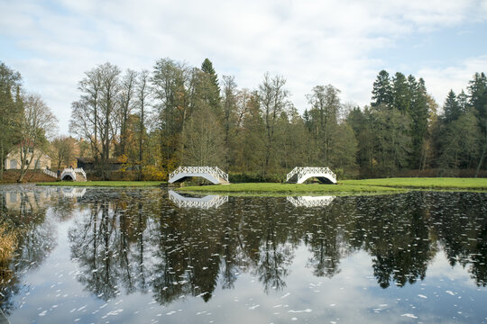 View of the calm lake mirroring the vibrant forest and white bridges under a bright sky, casting a serene reflection in Lahemaa National Park, Estonia.