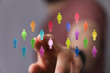 Concept of connection, community and teamwork. Digital hand touches colorful human icons representing diverse individuals in a network. Innovati