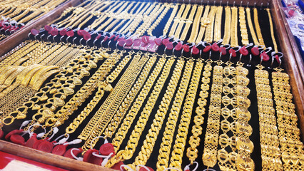 Gold jewelry, Rows of gold bracelet and necklaces displayed in jewelry store showcase, symbolizing...