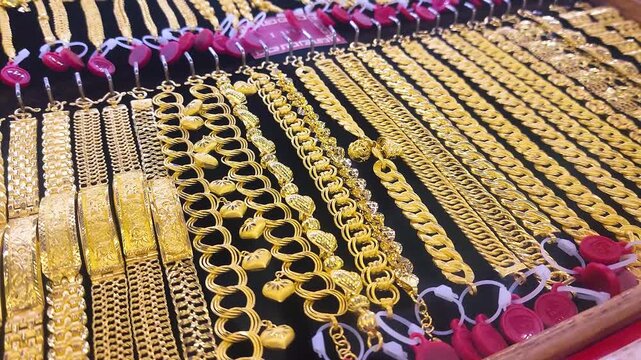 Gold jewelry, Rows of gold bracelet and necklaces displayed in jewelry store showcase, symbolizing wealth, investment, and luxury. Perfect for financial, economic, or gold market concepts
