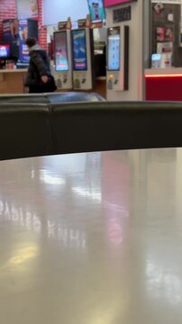 Unrecognizable man make an order and wait for an electronic queue on screen order number in a fast food restaurant. Blurred background. Vertical video