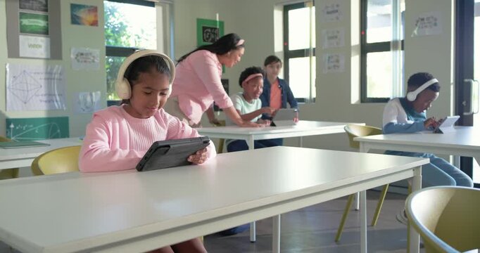 Camera pulling in youth girl pink top white headset adjusting tapping tablet front row engaging