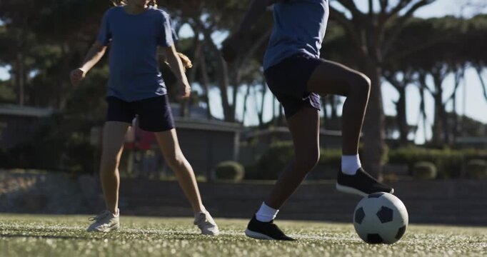 Stationary ball sending two teen soccer players into jostling on turf, defender taking possession
