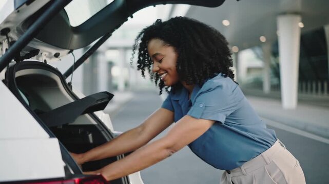Woman packs luggage into car at airport in daytime